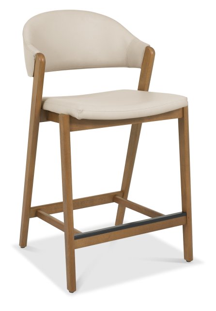 The Camden Counter Stool features a light beige upholstered seat and backrest, a curved wooden frame with legs, and a footrest, making it an ideal choice for those seeking stylish yet comfortable curved back stools.
