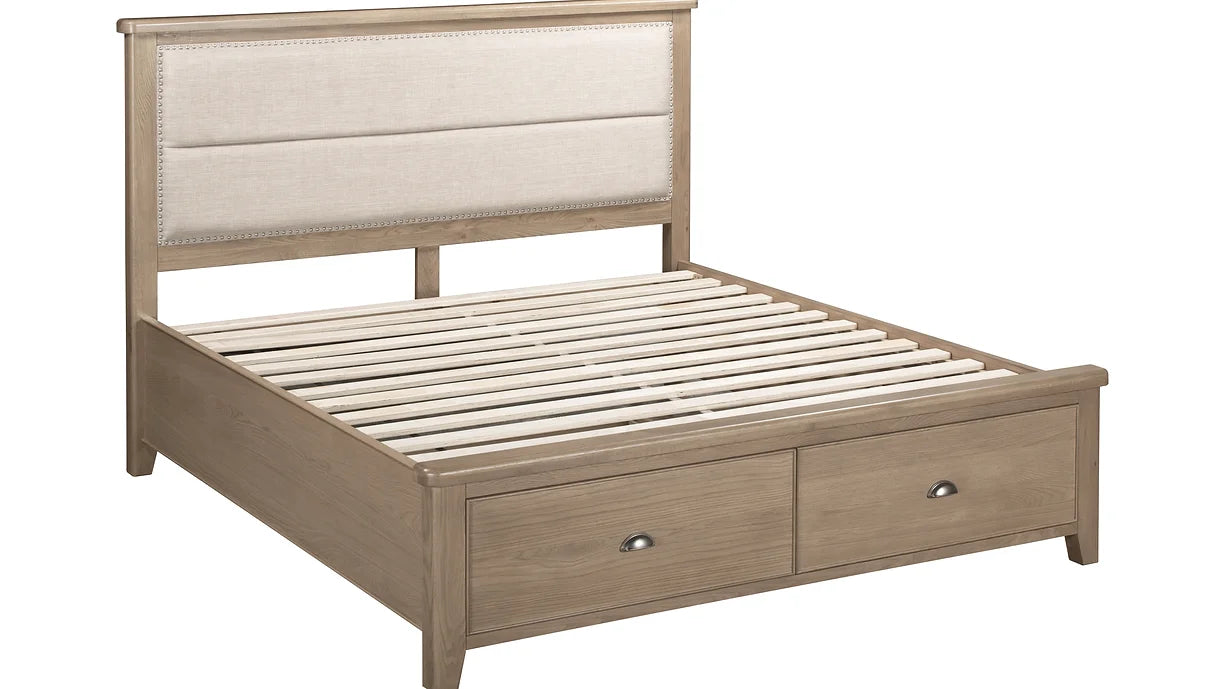 The Aylesbury bedframe boasts a beige padded headboard, two foot-end storage drawers, and sturdy wooden slats in an oak finish—combining stylish design and practical function for any bedroom.