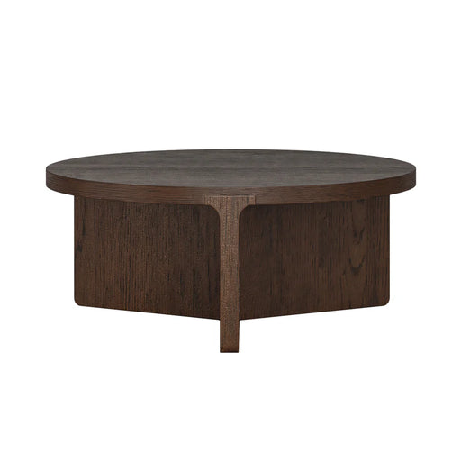 The California Coffee Table is a round, dark oak piece with a thick top and a geometric cross-shaped base, offering a modern, minimalist design.