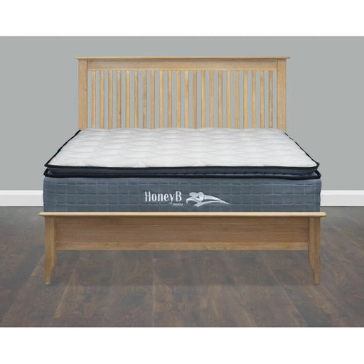 A mattress with pocket springs and a pillow top, stitched into the main body, covered with a grey fabric, branded as HONEYB, placed on a wooden bed frame.