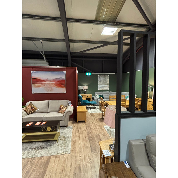 A showroom featuring the Edson Tv Unit alongside sofas, armchairs, wooden tables, and lamps on a wooden floor, with red and green accent walls. A large wall art piece and decorative items complete the stylish space.