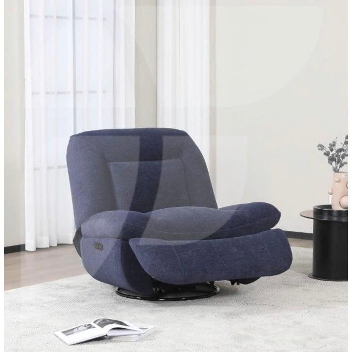 The Ebba Reclining Chair, featuring modern blue upholstery, electric recline, and an extended footrest, sits near a bright window with sheer curtains. A small black side table holds a vase and an open magazine close by.
