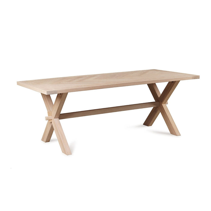 The Audrey Dining Table by vendor-unknown is a rectangular ash wood table with a light finish, featuring crossed legs at each end joined by a horizontal support beam.