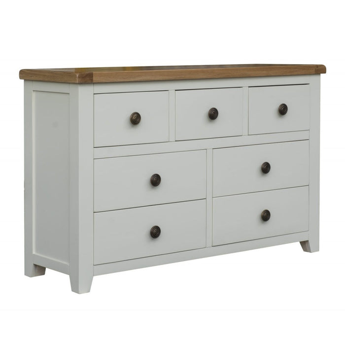 The Skellig wide chest by vendor-unknown is a white wooden dresser with a natural oak top, featuring three small drawers above four larger ones, all with round dark handles. Part of our chunky cream bedroom furniture collection.