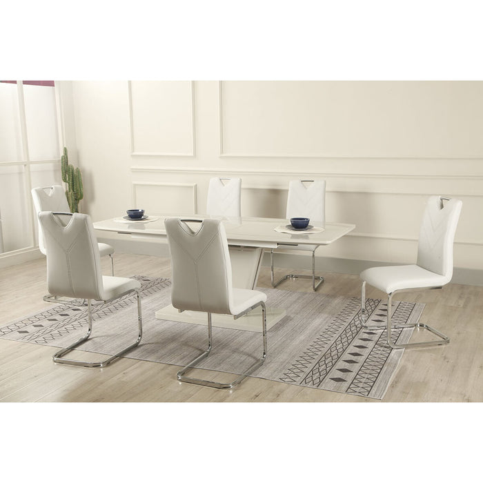 A modern dining room with the Vicenza table & 6 chairs by vendor-unknown, featuring a high gloss white rectangular table, six white cushioned chrome-leg chairs, a patterned rug, and a cactus in the corner against light walls.