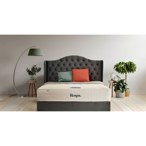 Respa mattress on a dark upholstered bed frame with a tufted headboard in a modern bedroom.