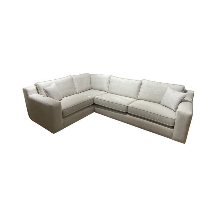 The Alice Corner Group is a light beige, L-shaped sofa with plush cushions and wide armrests, made from durable aqua clean fabric, displayed against a plain white background.