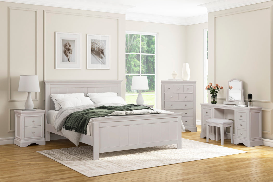 A bright, modern bedroom featuring the Lima Bedroom Range: elegant taupe furniture including a bed, nightstands with lamps, a dresser, vanity with mirror and stool—all illuminated by large windows.