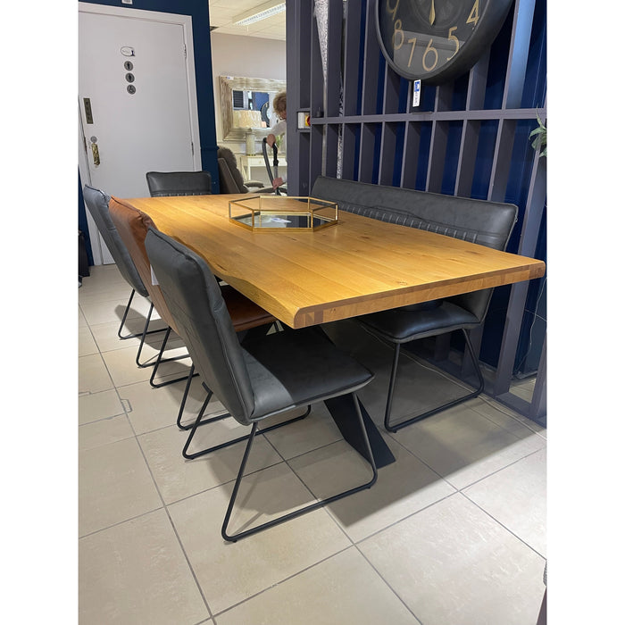 A modern dining area featuring the Richmond 2.1 Table & 6 Richmond Chairs by vendor-unknown, a metal centerpiece tray on the table, tiled floors, dark blue walls, and a large round wall clock in the background.