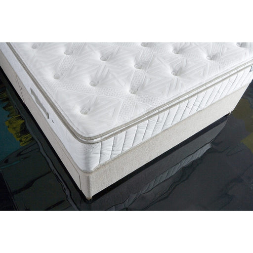 Close-up of the King Koil Boutique Sleep 1500, a white, quilted pocket spring mattress with tufted detailing, set on a light box spring atop a glossy black floor.