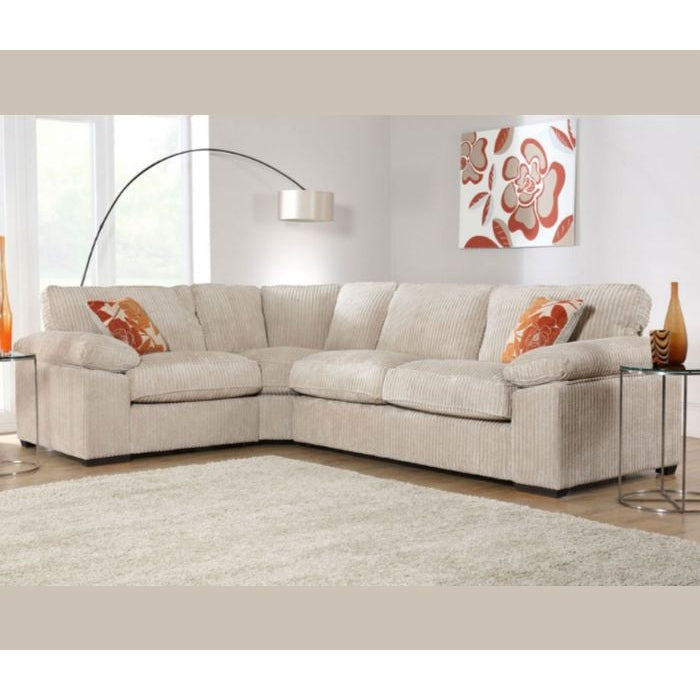 The Dexter Corner sectional by vendor-unknown, in beige with orange floral pillows, is arranged in a bright living room with a beige rug, glass side tables, a modern floor lamp, floral wall art, and light from large windows.