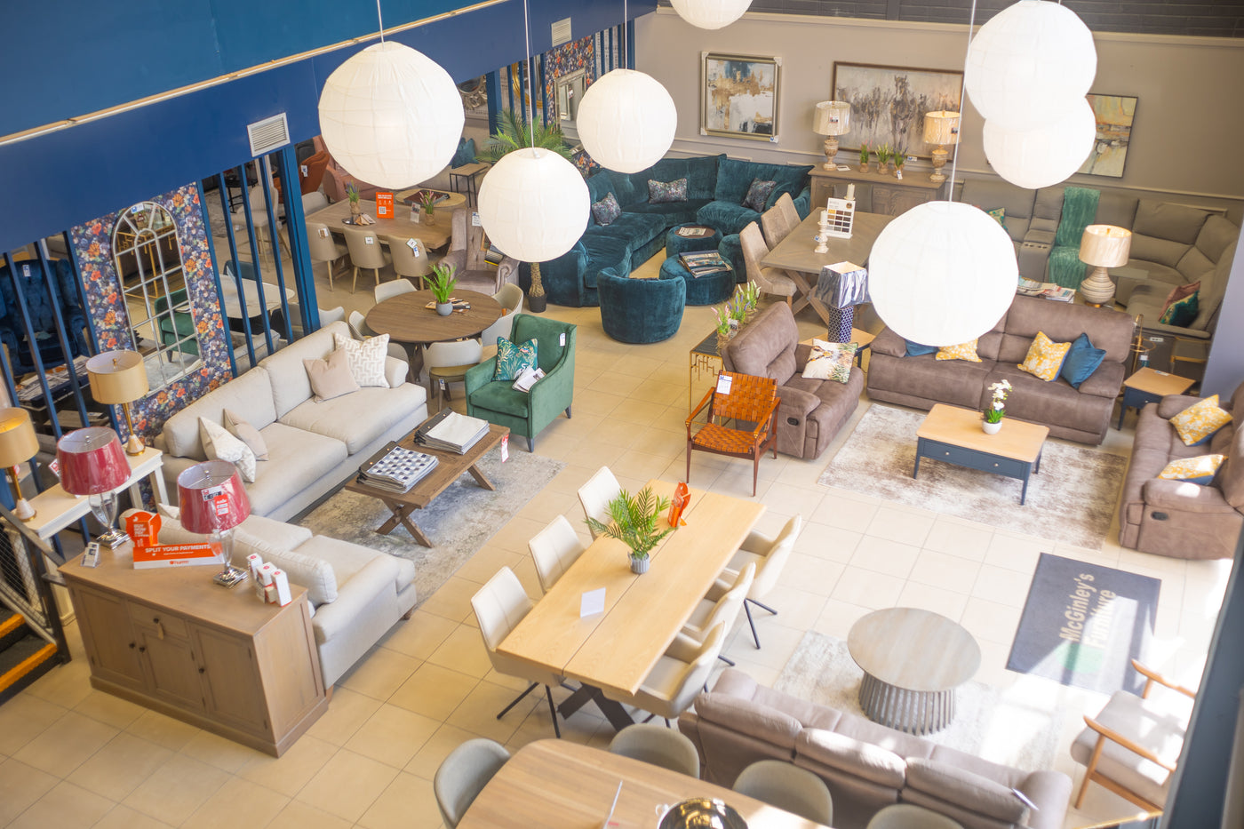 High-angle view of a well-lit furniture showroom floor featuring various living room and dining room sets in modern and transitional styles.