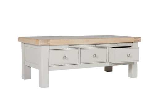 Rectangular table with a natural wood top and a painted gray base featuring three storage drawers, one of which is open.