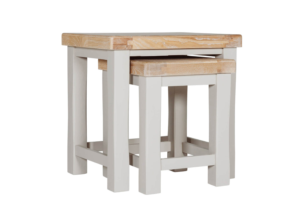 The Doune Nest of Tables features light oak tops and white painted legs, with the smaller table partially tucked under the larger one, all set against a plain white background.