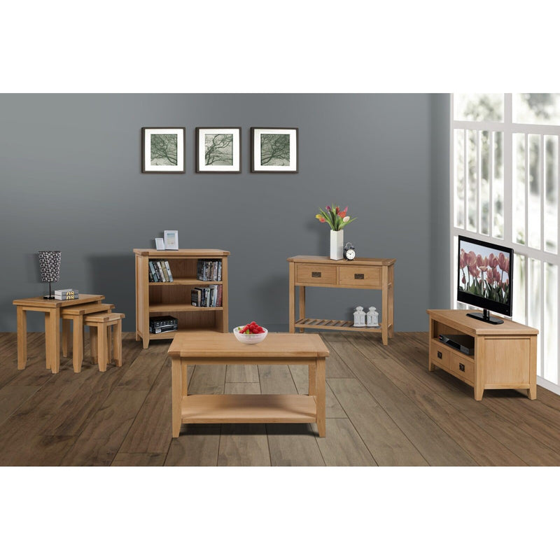 A modern living room with solid oak furniture, including the Saoirse Coffee Table, TV stand, bookshelf, side table set, and console table. Grey walls, wooden floor, three framed pictures, and large windows bring in natural light.