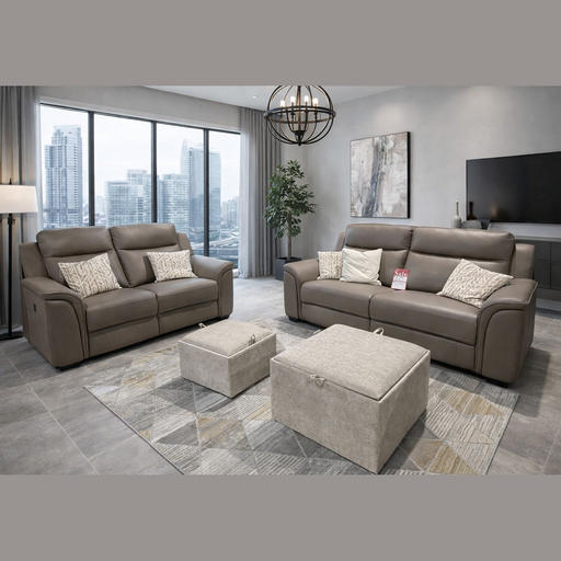 A modern living room with large windows showcases the Samantha 3+2 genuine leather sofa with patterned pillows, two beige ottomans, a geometric rug, floor lamp, potted plant, TV, and city buildings visible outside.