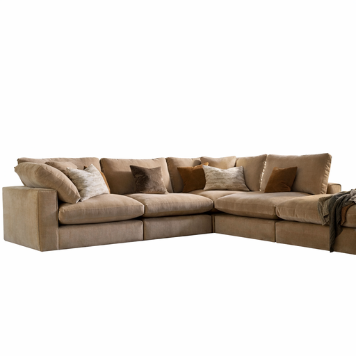 The Eden Corner Group is a large L-shaped beige sectional with deep fibre-filled seats, plush cushions, throw pillows, and a textured blanket over one end. Its cozy look stands out against the white background—ideal for spacious living rooms.