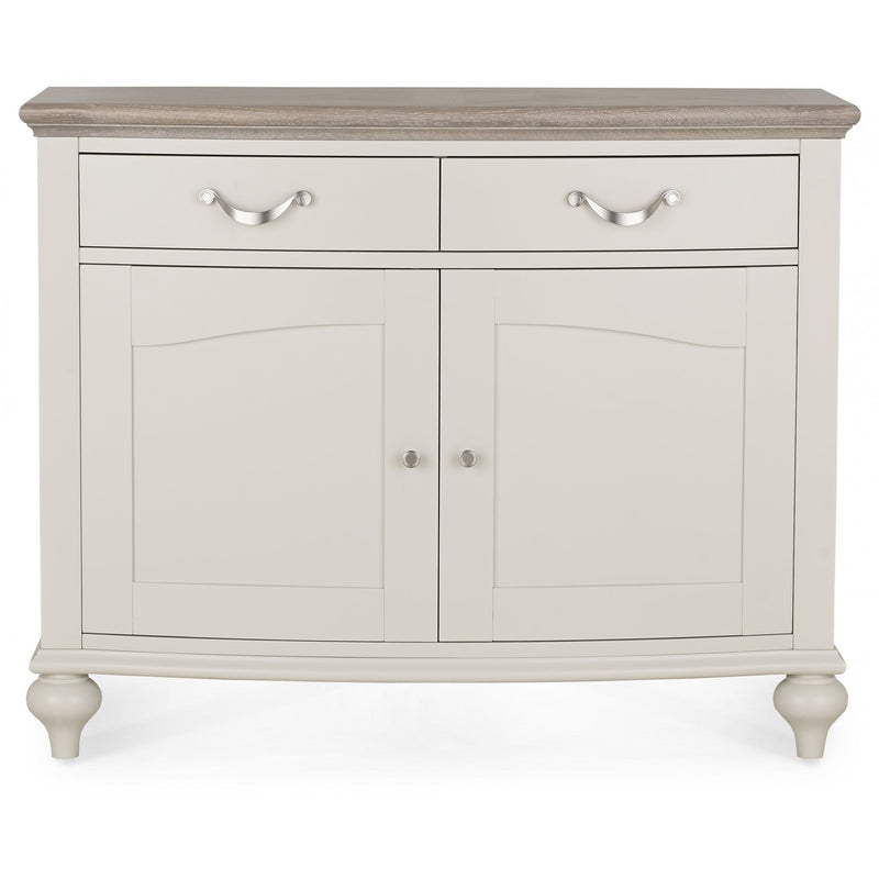 The Montreux Small Sideboard features a light gray finish, wood-finish top, two drawers with silver handles, and two cabinet doors with round knobs on rounded legs—perfect for grey washed oak furniture and modern dining tables.