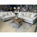 A modern living room features two light gray sofas from the Monroe Sofa Range, accented with beige and patterned Irish fabric cushions. A wooden coffee table, gray rug, decorative items, floor lamps, and a floral wall complete the look.
