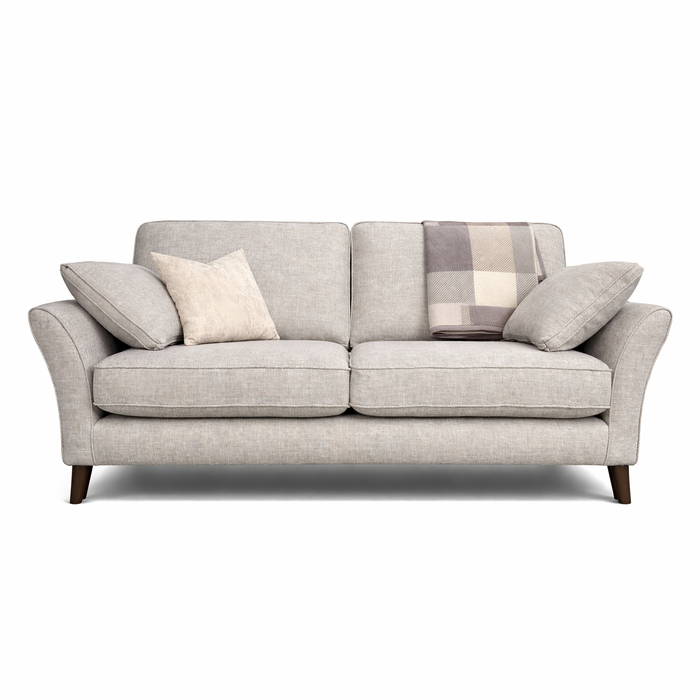 The Retro Sofa Range is a light gray, made-to-order sofa with angled armrests, two seat cushions, dark wooden legs, beech frames, two matching side pillows, a cream pillow, and a plaid blanket draped over the backrest.