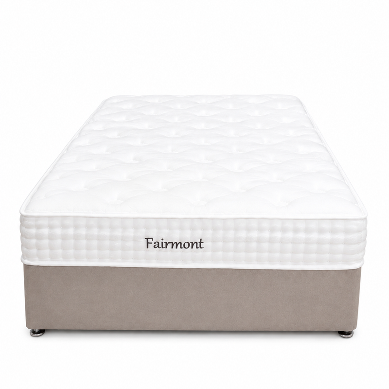 The Fairmont Mattress - Best Seller features a white quilted top, beige fabric base with casters, and "Fairmont" embroidered on the side. Shot from the front against a white background, it offers comfort and pressure relief.