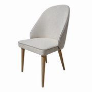 The Slim dining chair features a modern, minimalist design with a light beige upholstered seat and backrest, supported by four wooden legs. Shown against a white background.