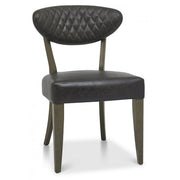 The Ellipse Fumed Oak Upholstered Chair, featuring a black diamond-patterned curved backrest, square seat, and wooden frame, complements rustic oak dining tables for a chic industrial look.