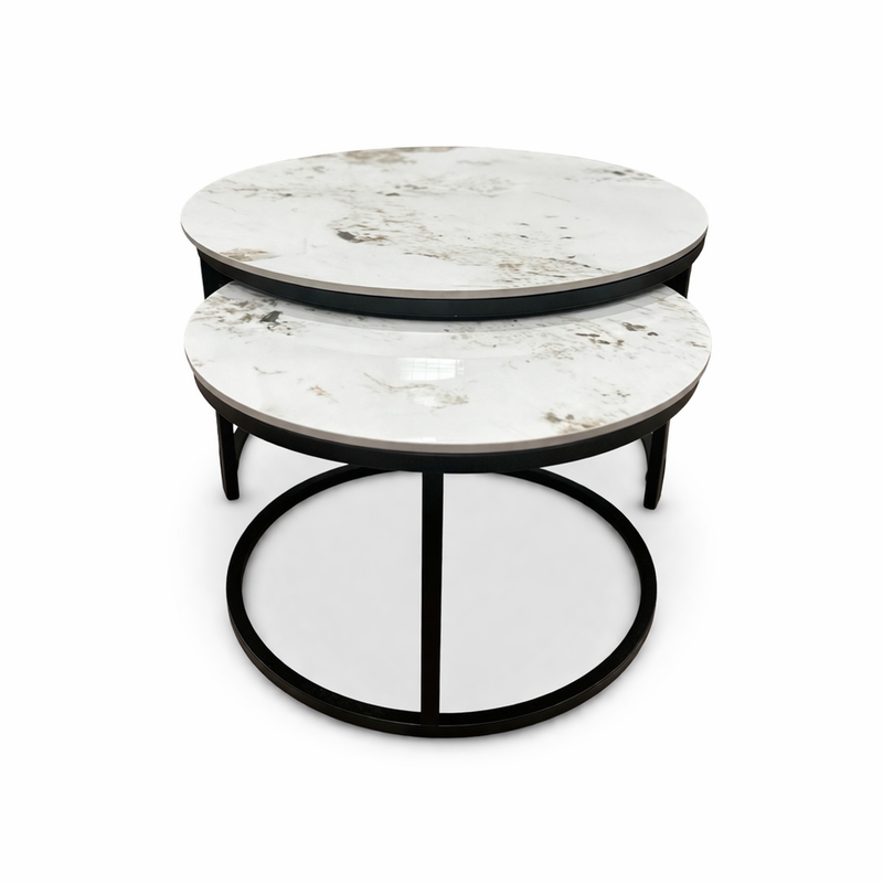The Kas Nest features two round nesting coffee tables with white marble tops and black metal frames, one smaller table partly tucked under the larger, both displayed on a white background.