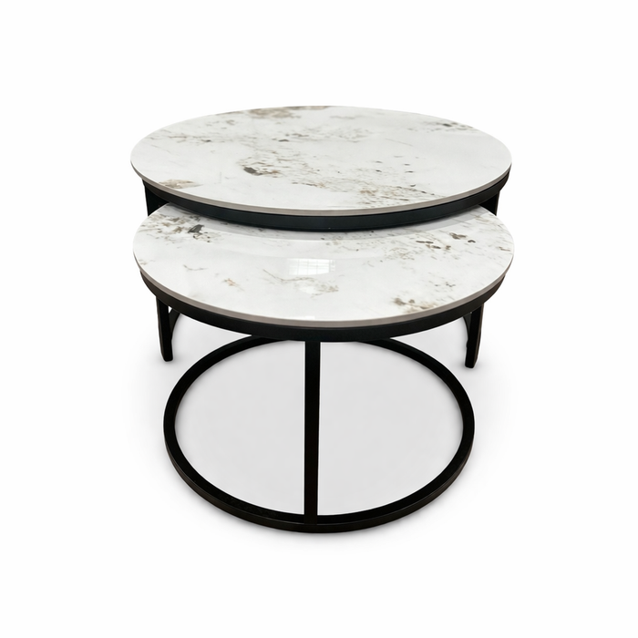 The Kas Nest features two round nesting coffee tables with white marble tops and black metal frames, one smaller table partly tucked under the larger, both displayed on a white background.