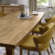 The Camden Dining Table features a solid wooden frame and is shown with a tray and a plate placed on top.