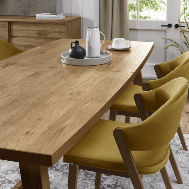 The Camden Dining Table features a solid wooden frame and is shown with a tray and a plate placed on top.