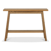 The Camden Console Table features a rectangular top, angled legs, and a lower shelf in light brown finish, and pairs beautifully with oak table tops from the Camden dining collection.