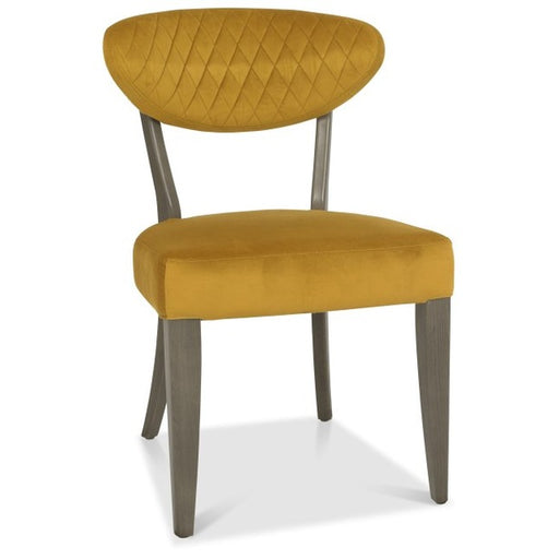 The Ellipse Fumed Oak Upholstered Chair features a mustard yellow quilted, curved backrest and straight dark wooden legs, making it an ideal match for industrial-style furniture.