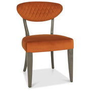 The Ellipse Fumed Oak Upholstered Chair features a cushioned orange seat, quilted back, and dark fumed oak legs—an ideal match for a rustic oak dining table, creating a stylish and cohesive dining space.