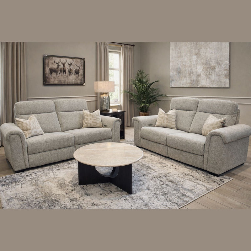 A living room featuring a modern sofa and the Luna Electric Recliner in light gray, a round marble coffee table, patterned rug, lamp on a side table, potted plant, and artwork on beige walls bathed in natural light.