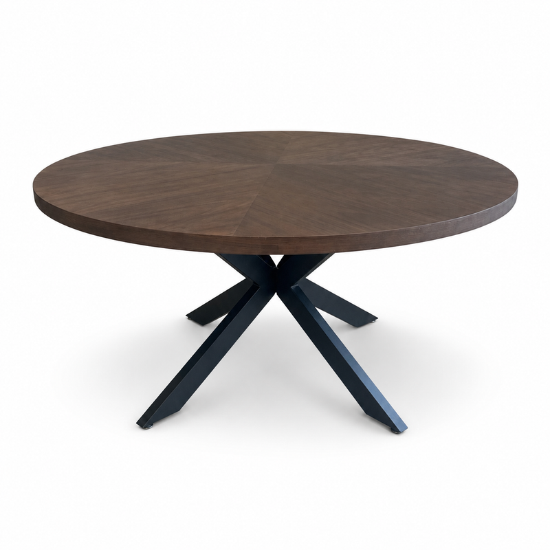The Olson 1.5 Round Dining Table features a dark timber top and intersecting black metal X-shaped legs, comfortably seating six, shown against a white background.