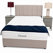 A beige Fairmont Divan Set - Special with stylish headboard, white mattress, dark blue blanket at the foot, and matching nightstands with lamps on either side, all set against a plain white background.