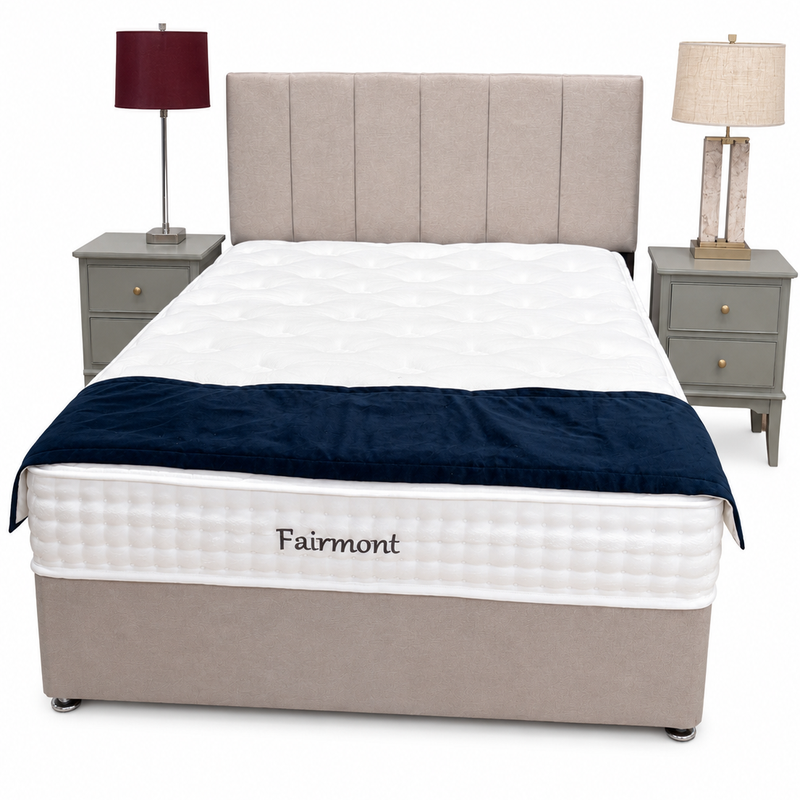 A beige Fairmont Divan Set - Special with stylish headboard, white mattress, dark blue blanket at the foot, and matching nightstands with lamps on either side, all set against a plain white background.