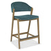 The Camden Counter Stool features light wooden legs, a teal upholstered seat and backrest, a low curved retro-inspired back, and a footrest across the front two legs.