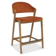 The Camden Counter Stool features a modern retro design with light wooden legs, an orange upholstered seat, and a curved backrest, shown against a white background.