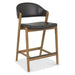 The Camden Counter Stool features a modern retro design with a wooden frame, angled legs, black cushioned seat, curved backrest, and a black front footrest bar for added comfort and style.