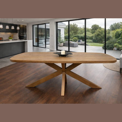 The Ashton Dining Table, made of solid ash wood with angled legs, stands on a dark floor in an open-plan room with glass doors to the patio. A square tray holding a white candle rests at its center.