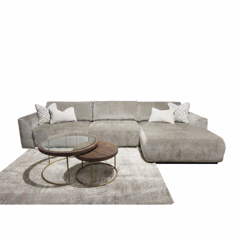 A modern living room setup featuring the Opus Chaise, a large gray modular sectional with Aquaclean Fabrics, two white patterned throw pillows, a light gray area rug, and two round nesting coffee tables with wood tops and gold metal frames.
