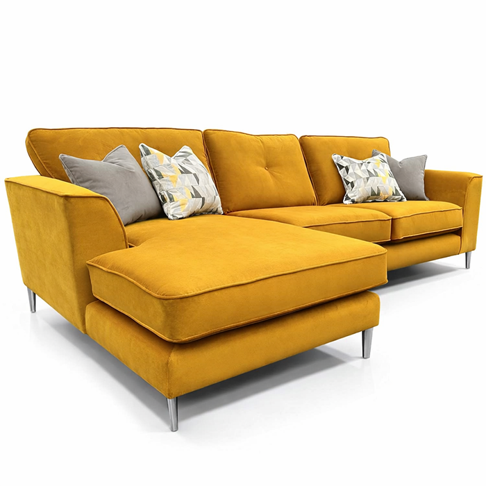 The Turino Chaise is a modern mustard yellow sectional with silver legs, a chaise lounge, and four grey and patterned pillows. Crafted from durable Aquaclean fabric, it offers easy maintenance and contemporary style.