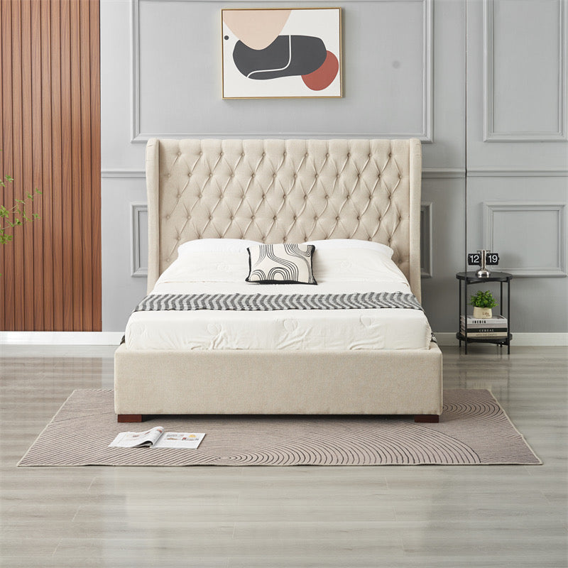 A modern bedroom showcases the Vienna Bedframe with a winged beige fabric headboard, white bedding, and a patterned pillow against gray paneled walls. A nightstand with decor, a plant, abstract art above the bed, rug, and open magazine complete the look.