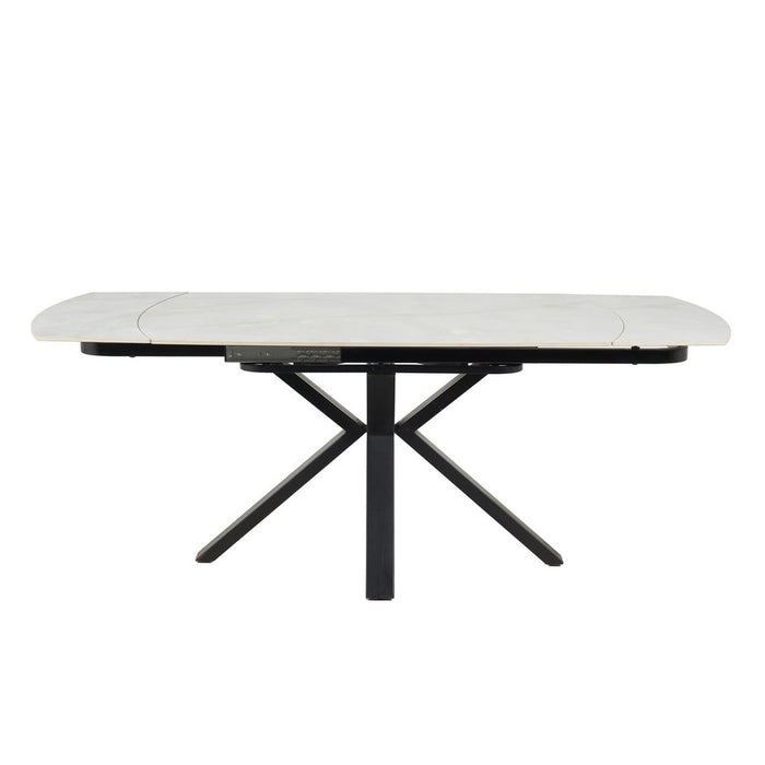 The Positano Swivel Dining Table showcases a modern rectangular form with a white marble ceramic top, rounded corners, and bold black crossed metal legs.