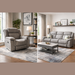A modern living room featuring a light gray Reno Recliner Sofa in washable fabric, paired with a coffee table, floor lamp, side table, potted plant, wall art, and large windows with beige curtains on wood floors and neutral rugs.
