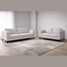 A modern living room features the Savannah 3+2 sofa set in stone fabric upholstery on a textured rug, with light walls, wooden flooring, and a window dressed in sheer white curtains.