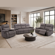 Modern living room featuring the Harper Recliner Range - Special in dark grey fabric, complemented by a round coffee table, light rug, large windows, and built-in shelves adorned with decor. Neutral tones and a minimalistic design enhance the cozy, inviting atmosphere while the contemporary recliner from the Harper range adds both comfort and style.