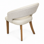 The Willow Dining Chair features a cream-colored seat, a curved upholstered backrest, and four wooden legs.